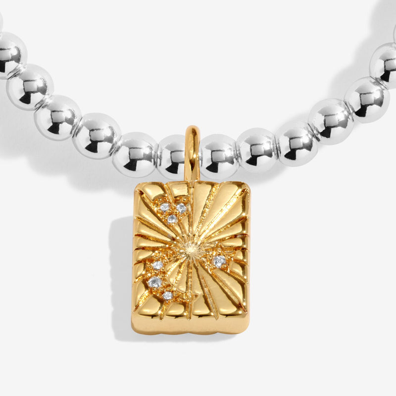 Close-up of gold-plated rectangular starburst charm with crystal details on beaded Bracelet