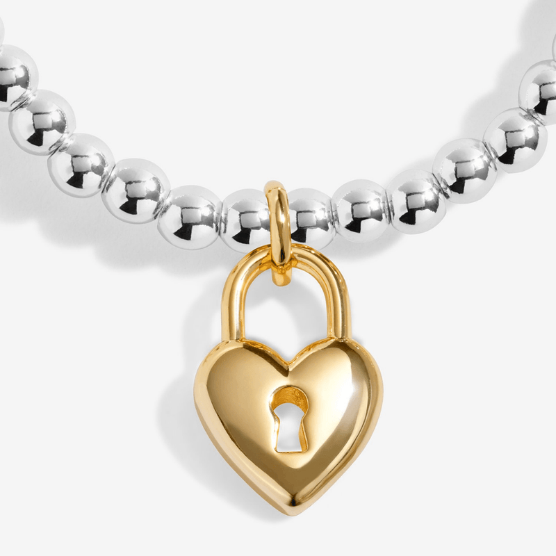 Close-up of the gold-plated heart padlock charm on a Joma bracelet