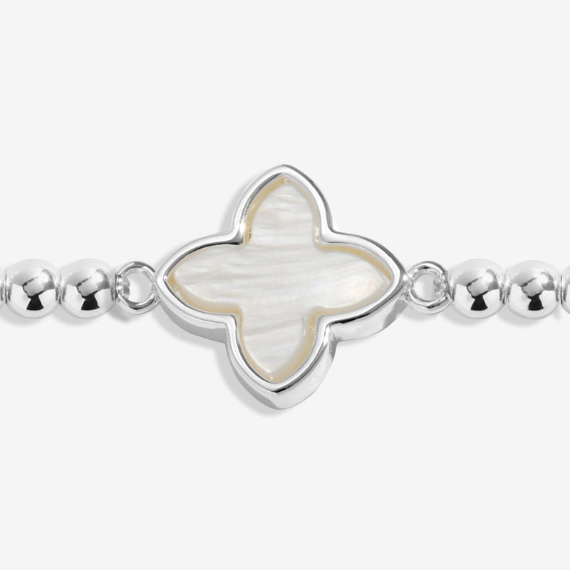 Close-up of mother of pearl clover charm on silver-plated beaded Bracelet