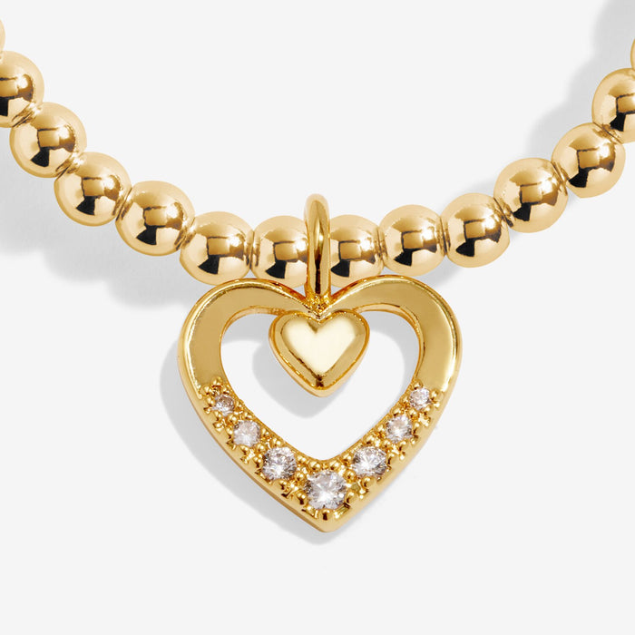 Close-up of Joma Jewellery gold-plated open heart charm with inner heart and sparkling crystal detail on a beaded Bracelet.
