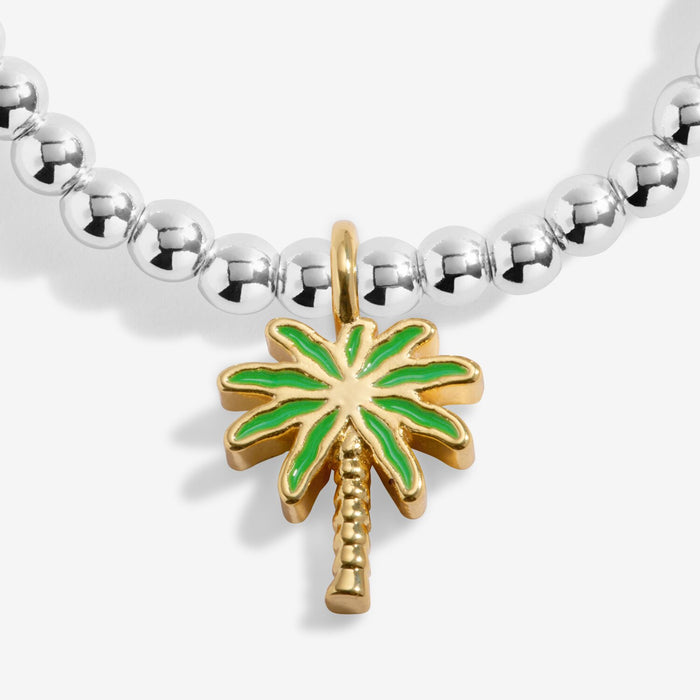 Close-up of gold-tone palm tree charm with green enamel on silver-plated beaded Bracelet