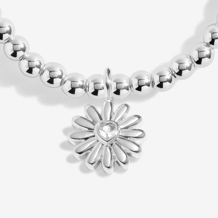 Close-up of Joma Jewellery daisy charm with heart-shaped crystal centre on a silver-plated beaded Bracelet.