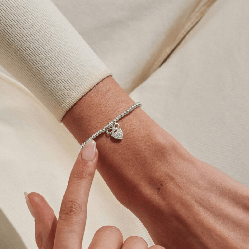 Joma Jewellery A Little Prom silver plated bracelet worn on wrist with sparkly heart and bow charm