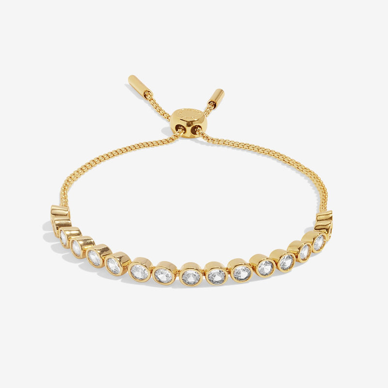 Angled view showing adjustable box‑chain slider clasp and sparkling crystal stations on the polished gold bracelet.
