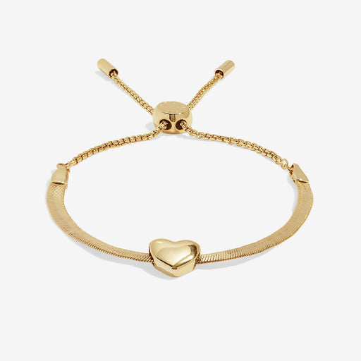 Angled view showing adjustable box‑chain slider and curved heart charm on the gold herringbone bracelet.

