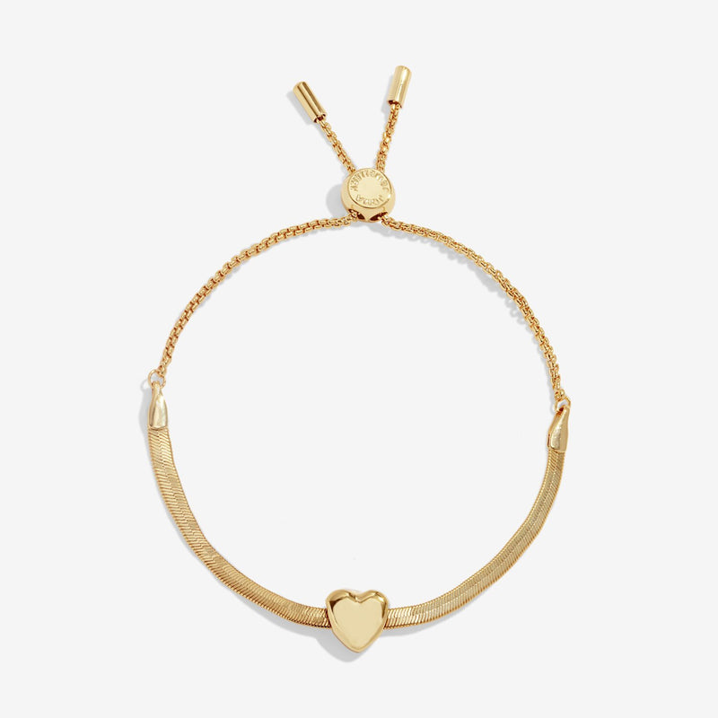 Joma Jewellery gold‑plated herringbone slider bracelet with polished heart slider charm, product shot on white background.
