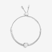 Joma Jewellery silver‑plated herringbone slider bracelet with polished heart charm, product shot on white background.
