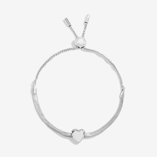 Joma Jewellery silver‑plated herringbone slider bracelet with polished heart charm, product shot on white background.
