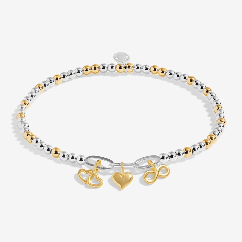 Two‑tone silver & gold beaded bracelet with three mixed‑metal charms – heart, infinity, interlocking hearts – on white background.

