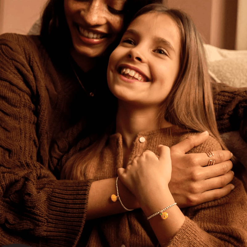 Child wearing Joma Jomees pumpkin bracelet with matching adult bracelet