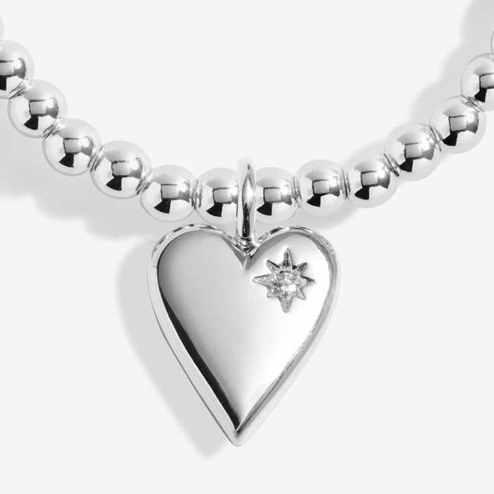 Close-up of Joma Jewellery heart charm with tiny star detail on a silver-plated beaded Bracelet.