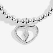 Close-up of Joma Jewellery open heart charm with dangling angel feather detail on a silver-plated beaded Bracelet.