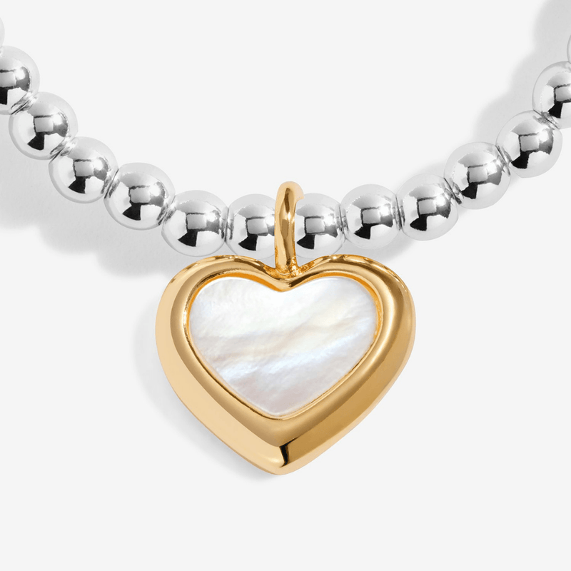 Close-up of gold-plated heart bracelet charm with pearly centre