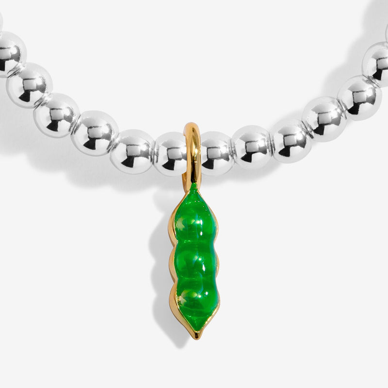 Close-up of green pea pod charm on silver-plated beaded Bracelet with gold-tone edging