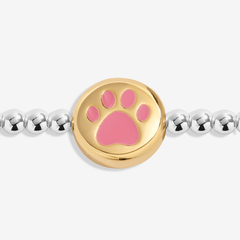 Close-up of gold-plated bracelet charm with a pink paw print