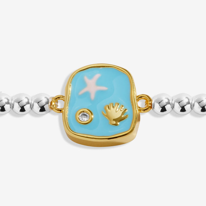 Close-up of blue enamel ocean charm on silver-plated beaded Bracelet with gold-tone starfish and shell icons