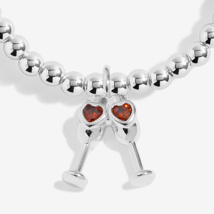 Close-up of champagne glasses charm with orange heart crystals on silver-plated beaded Bracelet