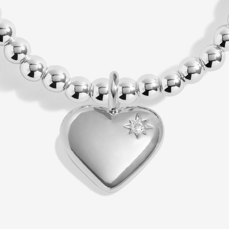 Close-up of silver heart charm with star-set crystal detail on silver beaded stretch Bracelet
