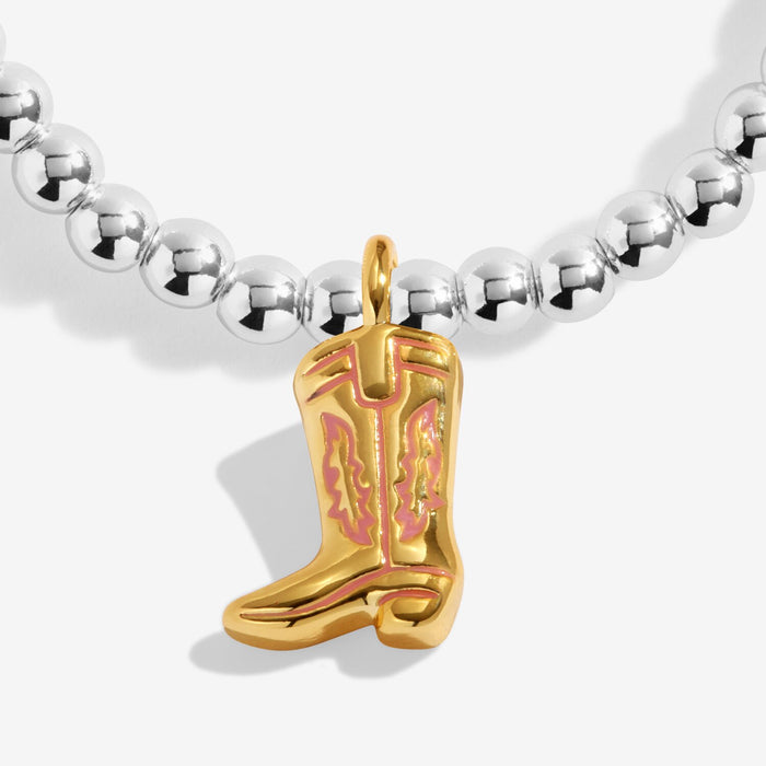 Close-up of gold-tone cowgirl boot charm with pink enamel on silver-plated beaded Bracelet