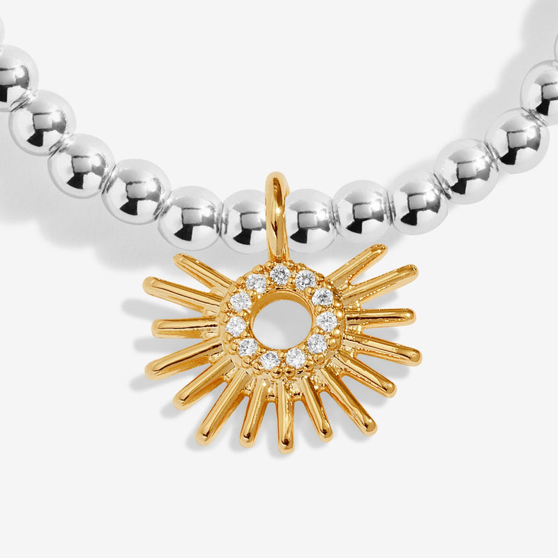 Close-up of gold sunburst charm with crystal circle detail on silver beaded stretch Bracelet