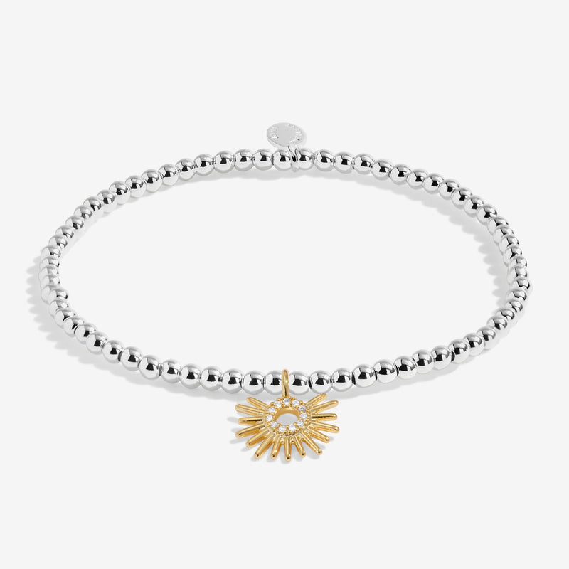 Joma stretch Bracelet with silver beads and gold sunburst charm displayed on a white background