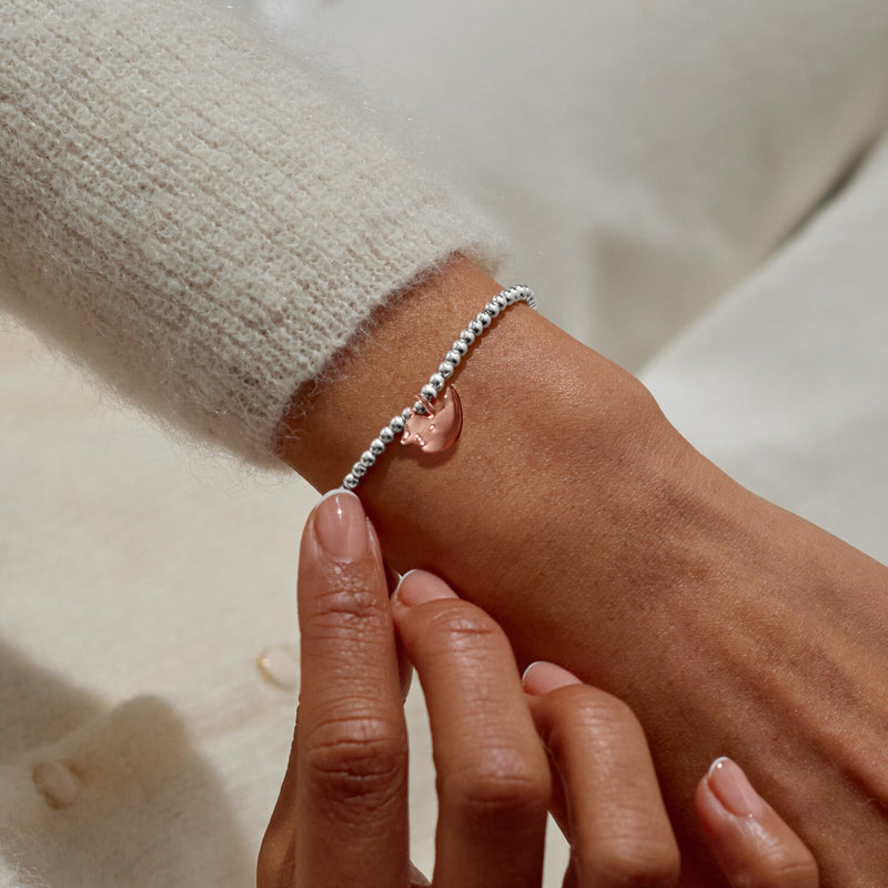 Christmas Robin rose‑gold charm bracelet styled on wrist – a delicate festive gift with silver stretch beads.
