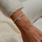 Fabulous Friend interlocking‑hearts charm bracelet styled on wrist – a delicate silver gift for your best friend.
