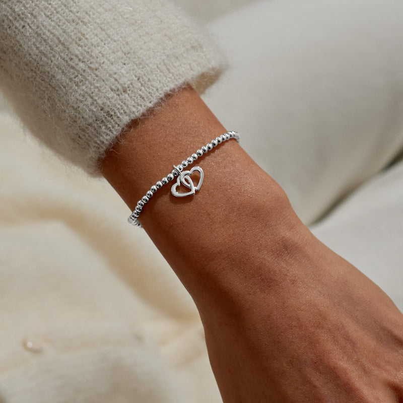 Fabulous Friend interlocking‑hearts charm bracelet styled on wrist – a delicate silver gift for your best friend.
