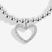 Close‑up of Joma Jewellery “Merry Christmas” bracelet pavé heart charm on polished beads – perfect stocking‑filler bracelets for women.
