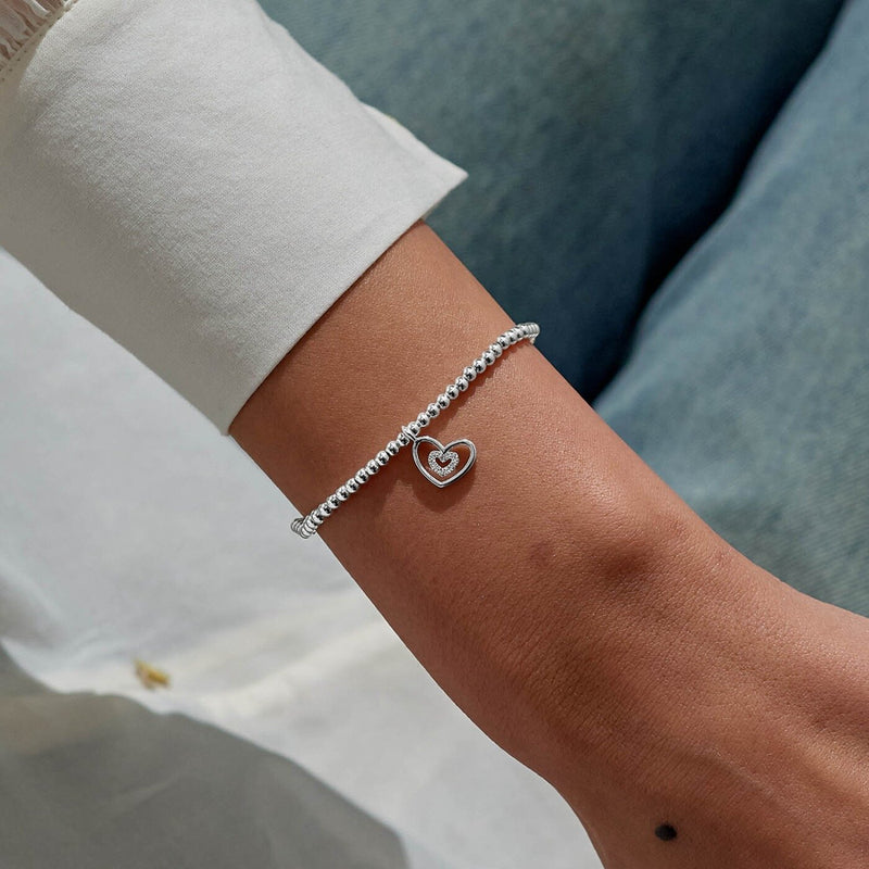 Double‑heart Christmas bracelet for Grandma styled on wrist – dainty silver beads and festive sparkle.

