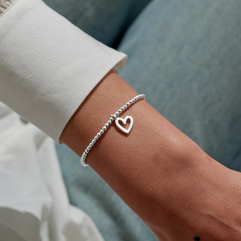 Delicate open‑heart charm bracelet styled on wrist – a festive gift that suits everyday wear.
