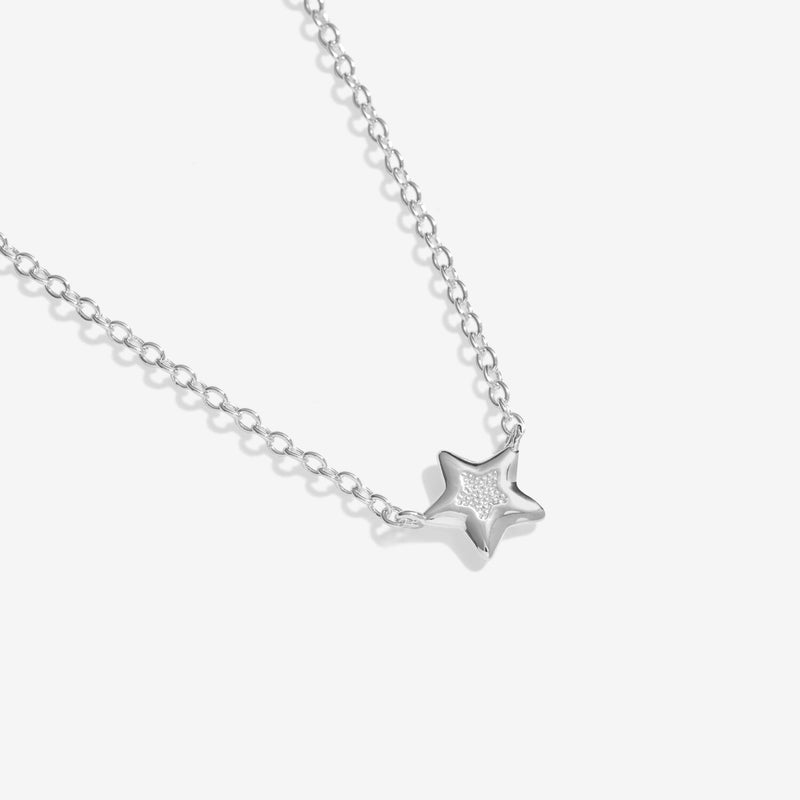Macro of petite polished star charm with pavé centre on fine silver necklace chain – festive jewellery detail.
