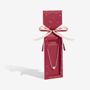 Red cracker‑style gift box displaying Joma Jewellery Merry Christmas silver star necklace ready to give.