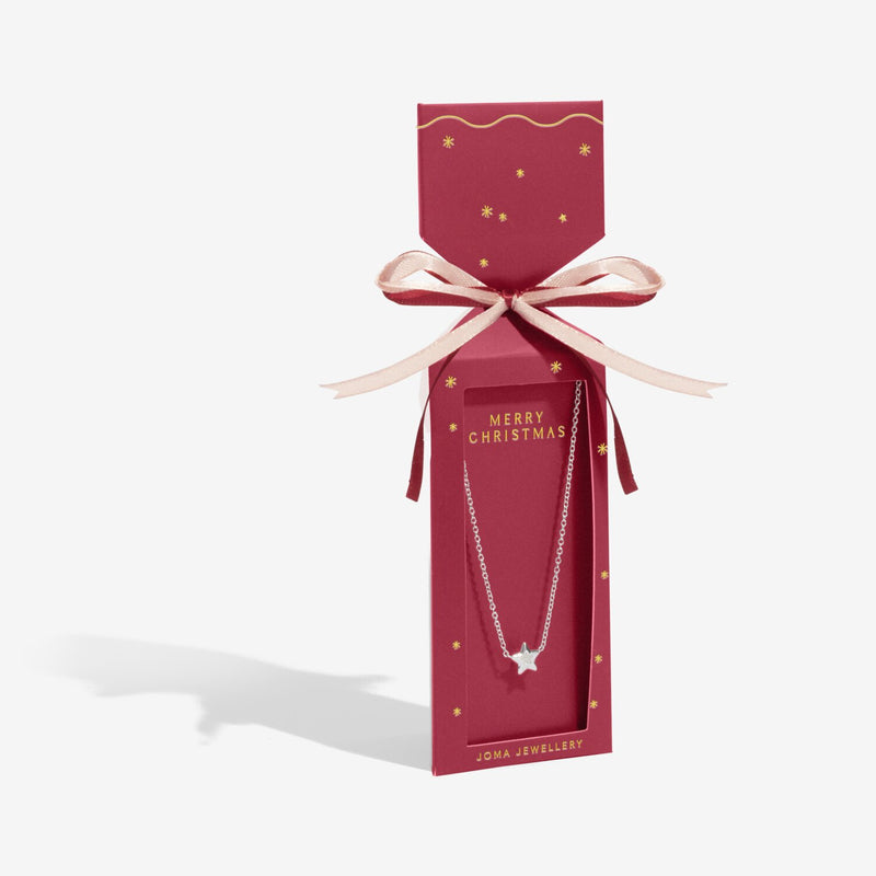 Red cracker‑style gift box displaying Joma Jewellery Merry Christmas silver star necklace ready to give.