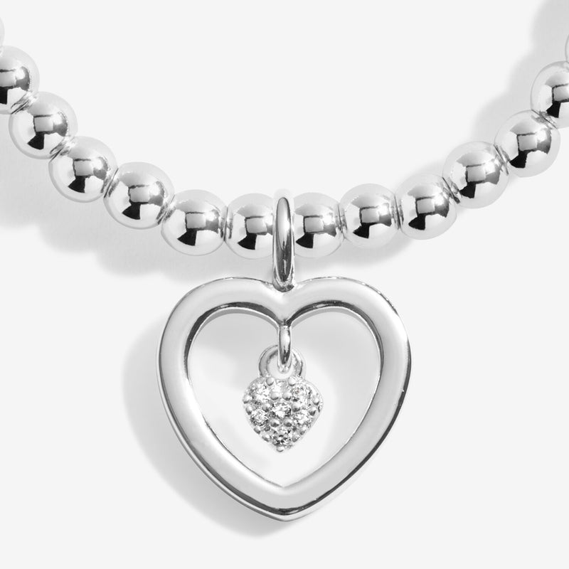 Close‑up of pavé mini‑heart suspended inside open‑heart charm on Joma Jewellery “One in a Million” bracelet.
