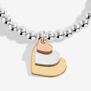 Close‑up of gold, silver & rose‑gold layered heart charms on Joma Jewellery beaded bracelet – elegant gifts for women.

