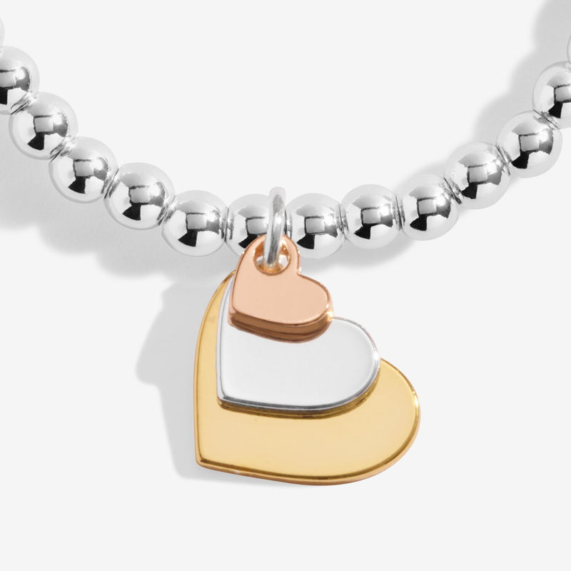 Close‑up of gold, silver & rose‑gold layered heart charms on Joma Jewellery beaded bracelet – elegant gifts for women.
