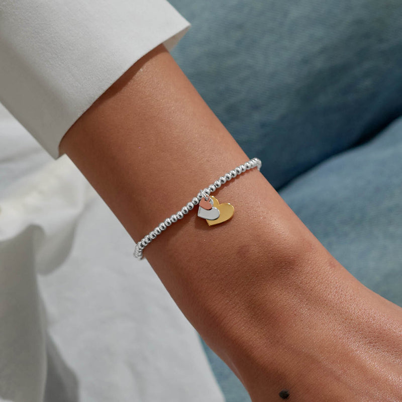 Tri‑tone heart charm bracelet by Joma Jewellery styled on wrist – chic everyday bracelets and perfect gifts for women.