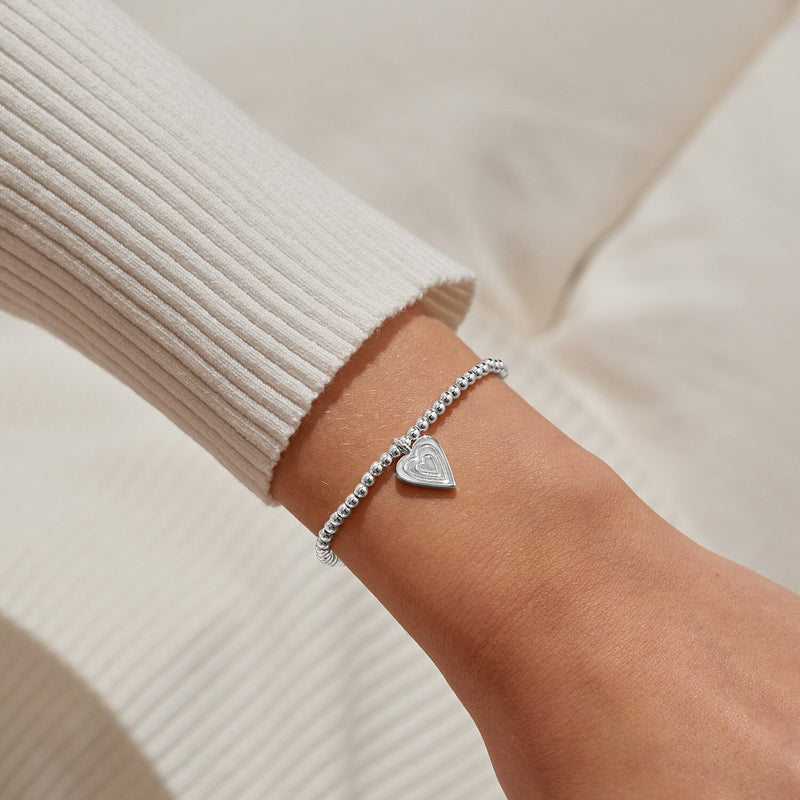 Dainty layered‑heart charm bracelet styled on wrist – a thoughtful silver gift to wear with love.
