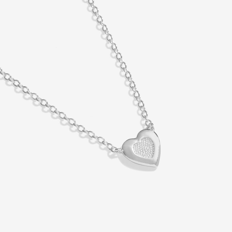 Close‑up of polished heart pendant featuring sparkling pavé centre on delicate adjustable silver chain.
