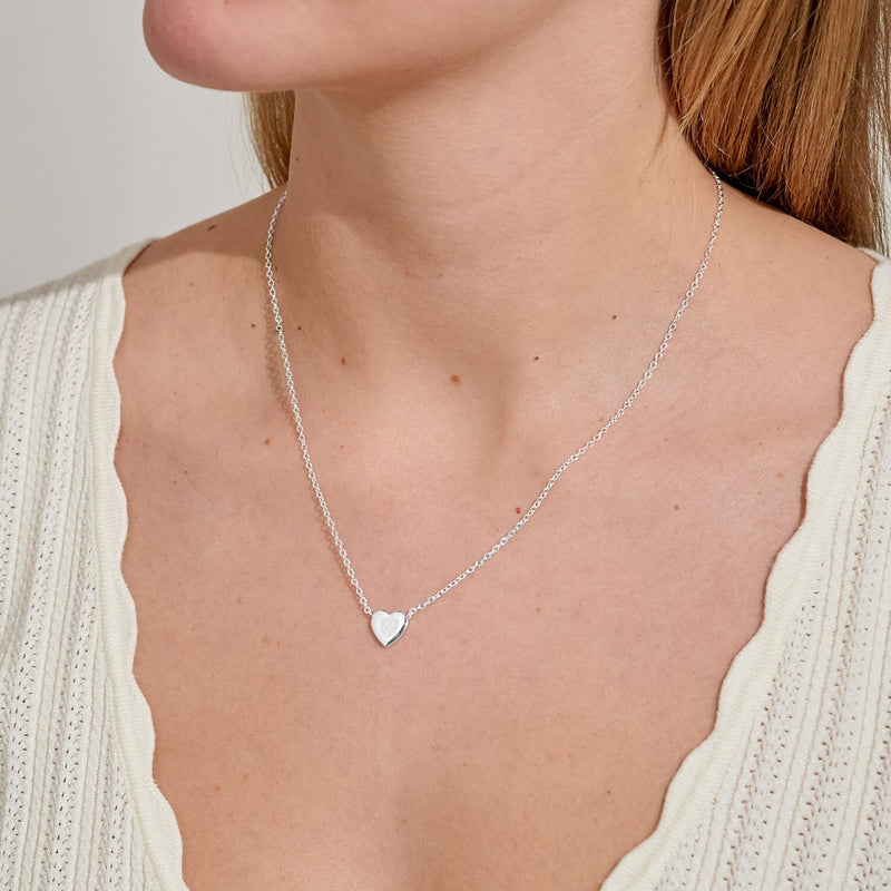 Minimal silver heart necklace resting at collarbone – everyday jewellery gift to show love.
