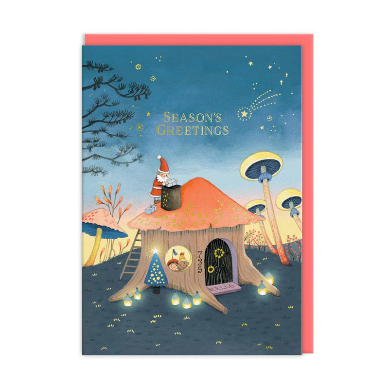 Whimsical Christmas card by Joo Joo Paper with tiny Santa on a mushroom-roof cottage under a starry sky; Season’s Greetings text, neon accents; A6, blank inside, coral envelope