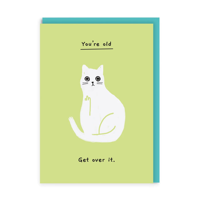 Lime green birthday card with white cat making a cheeky raised paw gesture; text reads “You’re old … Get over it.” A6, blank inside, aqua envelope by Ken The Cat