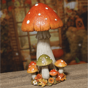 Lifestyle view of a tall autumn mushroom decoration on a wooden surface with a rustic backdrop.