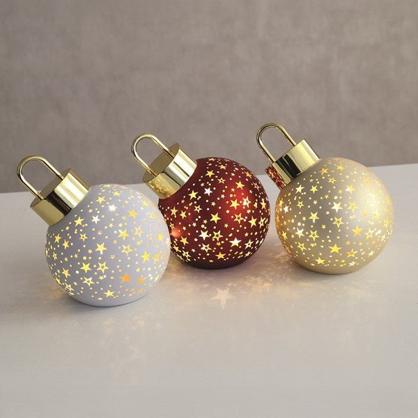 Three LED baubles in red, gold and grey with star designs glowing on a table.

