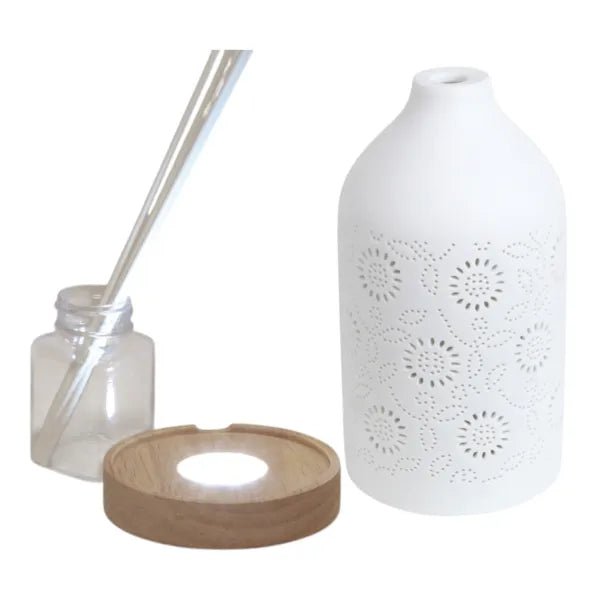 Reed diffuser set components including ceramic cover, wooden LED base, bottle and reed sticks.