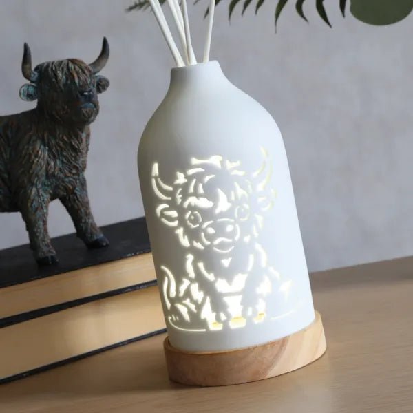 LED Highland cow ceramic reed diffuser glowing in a styled setting on a tabletop.