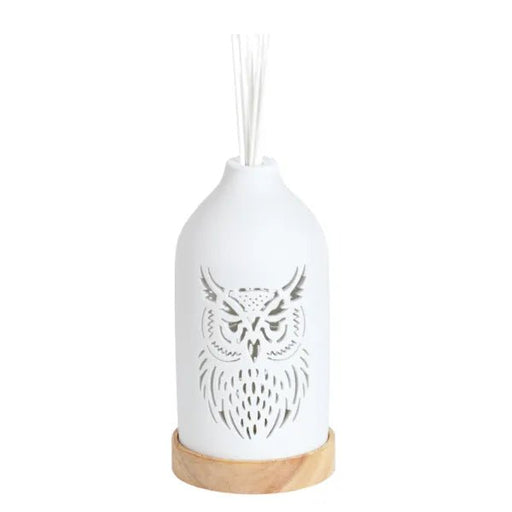 White ceramic owl reed diffuser assembled on a wooden base with reed sticks in place.
