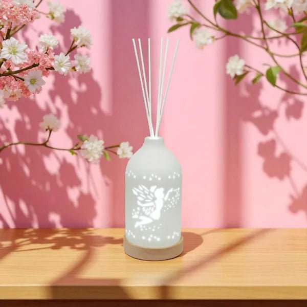 Fairy LED reed diffuser glowing on a table with pink background and cherry blossoms

