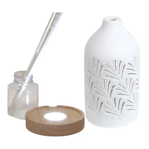 Disassembled reed diffuser with ceramic cover, base, glass bottle, and reed sticks

